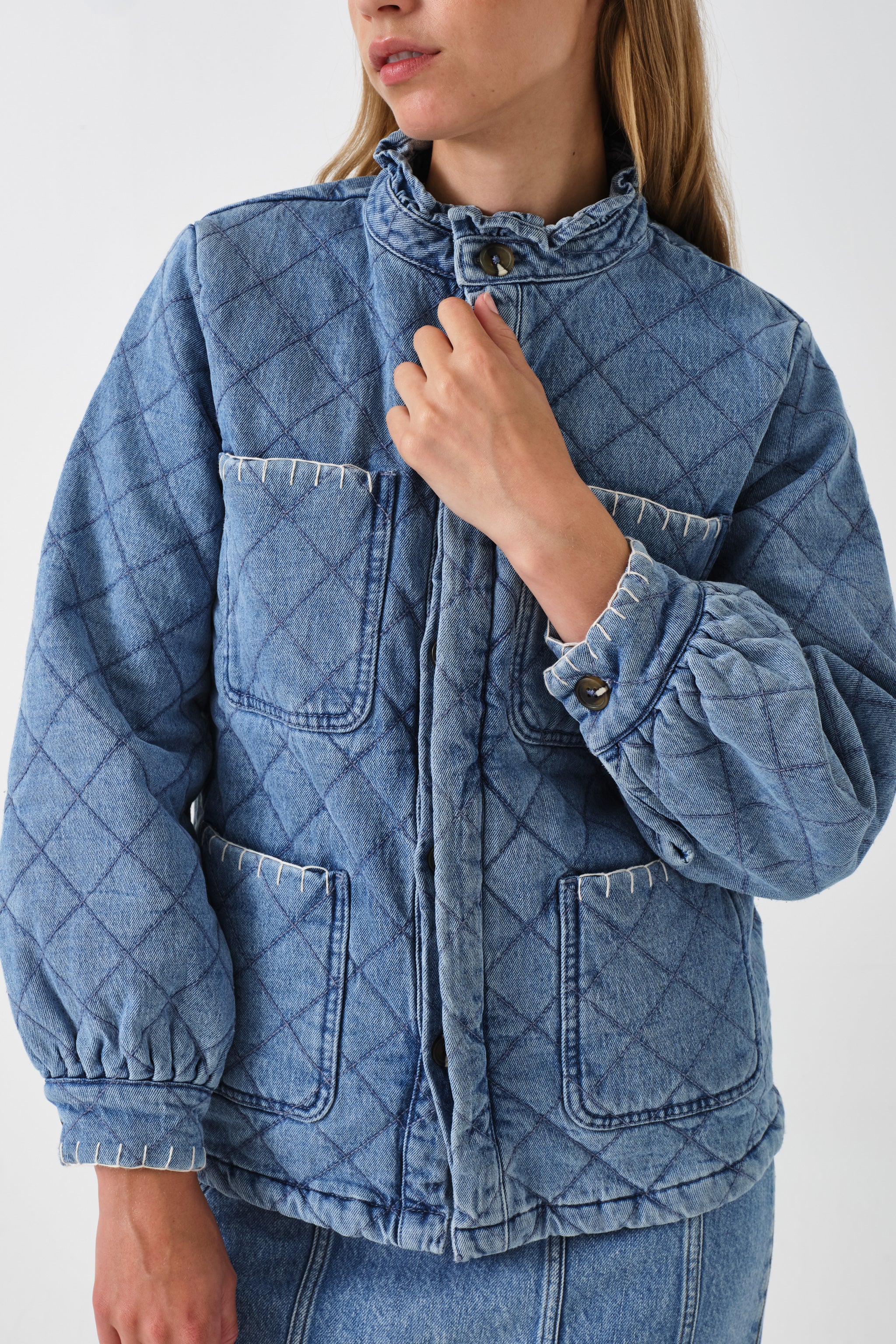 Woman wearing a blue quilted denim jacket on a white background
