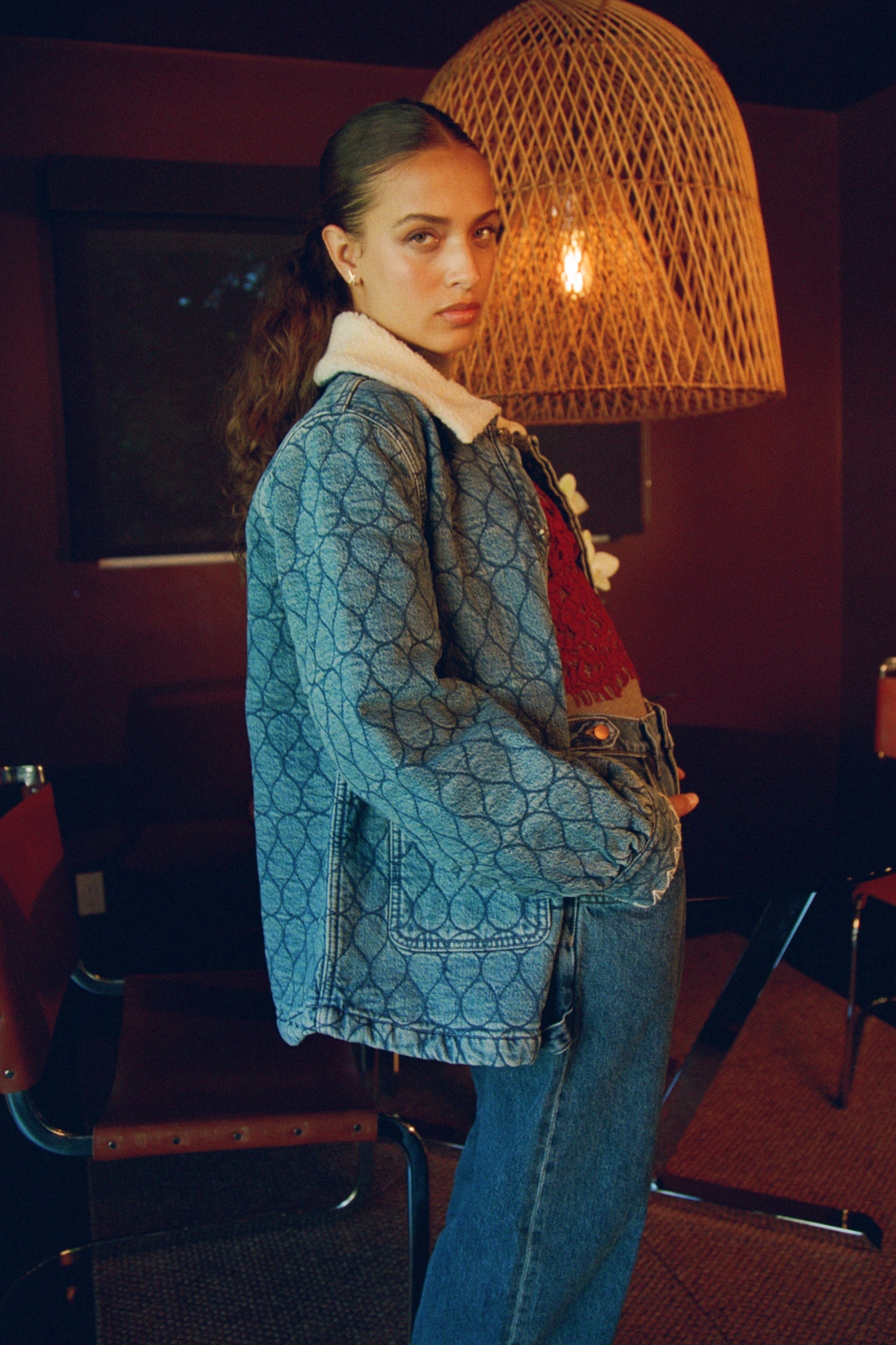 Woman wearing a blue quilted patterned jacket with a removable sherpa collar and blue jeans 