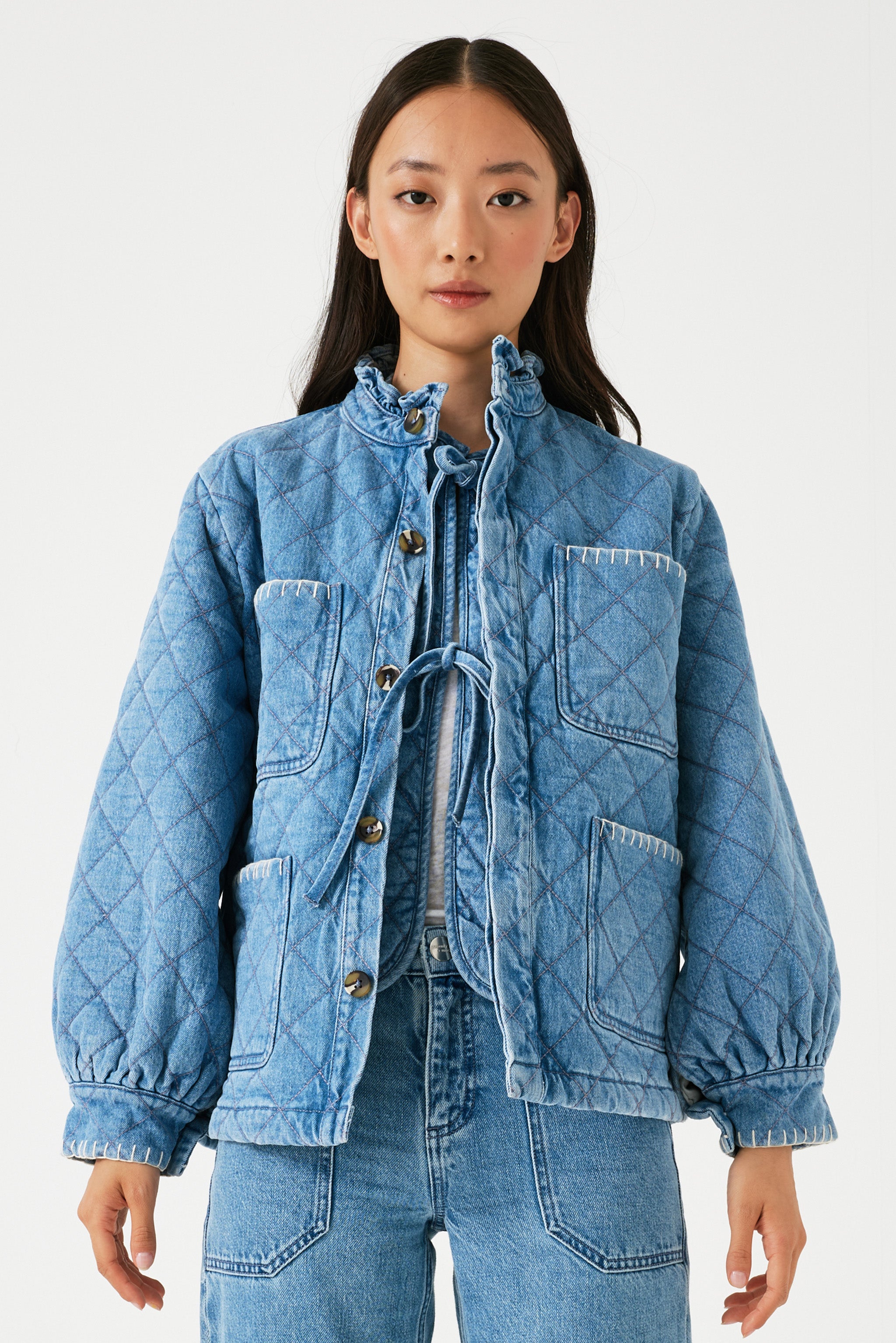 Woman wearing a blue quilted jacket with a frill collar
