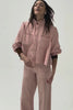 woman wearing light pink high waisted, wide, cropped jeans with big pockets, a pink shirt, and brown shoes on a white background
