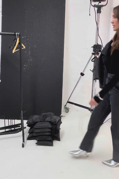 woman holding a black denim dress / long jacket with silver studs (embellishments) and a tailored cinched waist 